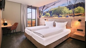 A hotel room with a large bed, a desk with a chair, and a scenic mural on the wall. - Hotel-Restaurant Berghof (Petersberg)