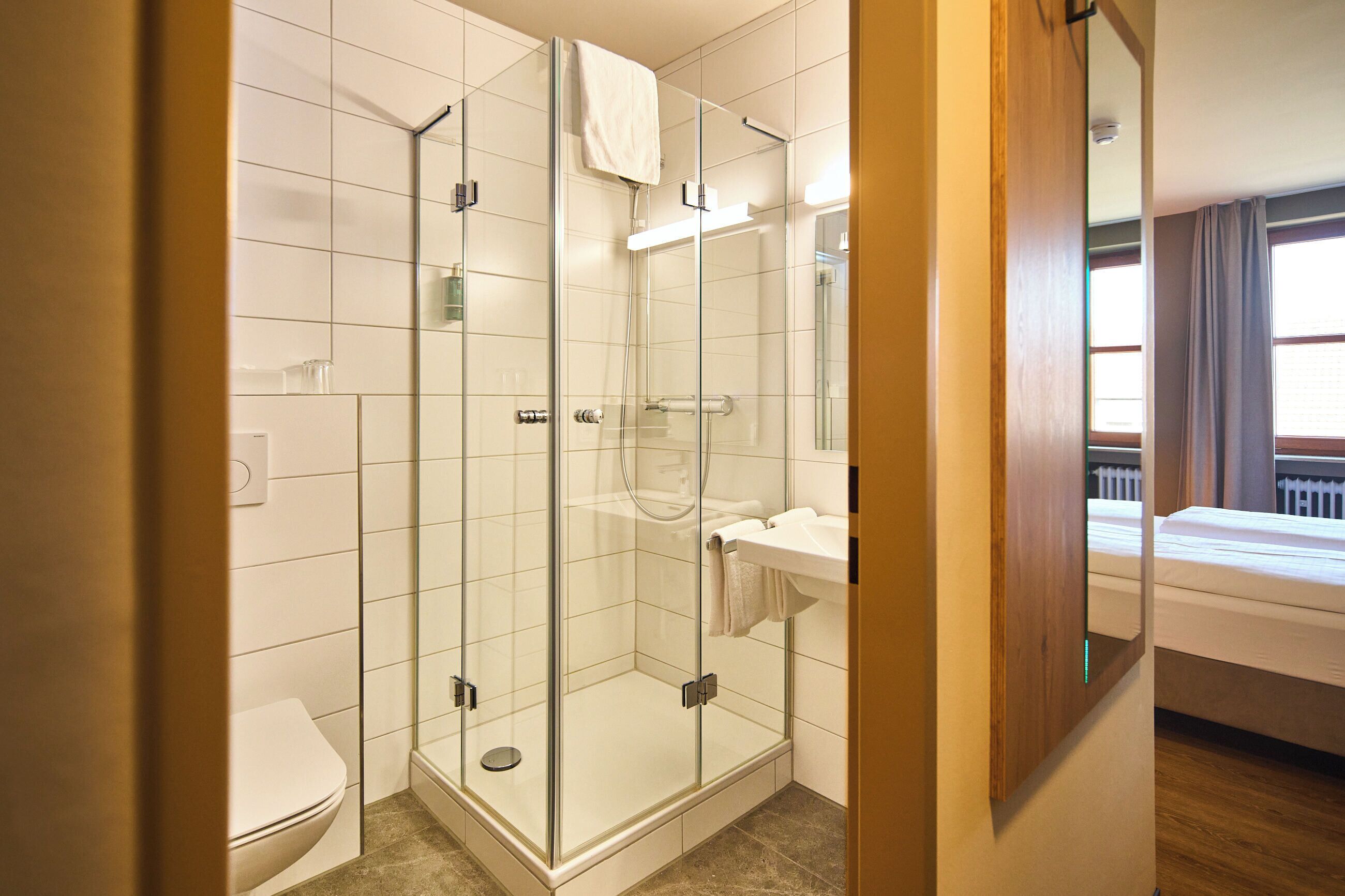 Un baño moderno con ducha de mampara de vidrio, inodoro y lavamanos.
