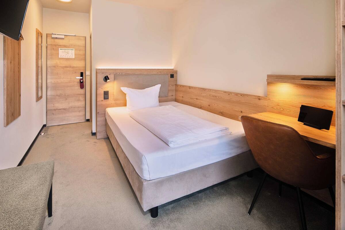 A hotel room with a bed, a desk, and a chair.