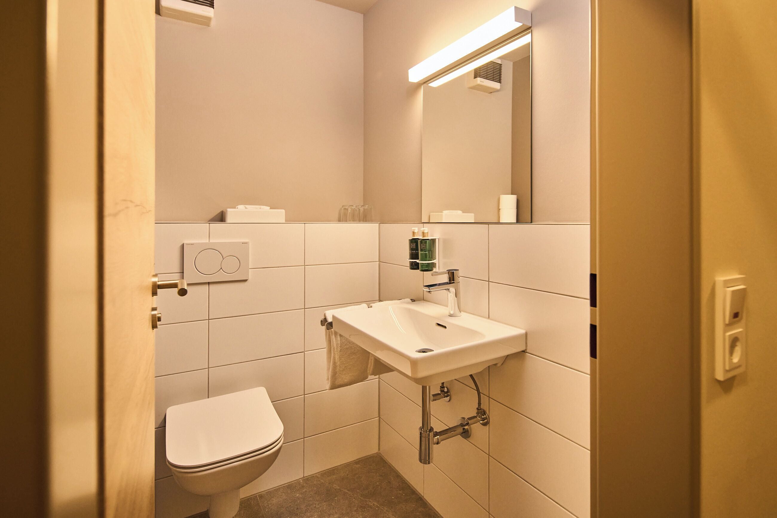 Un baño pequeño y limpio con inodoro, lavamanos y espejo.