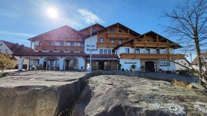 A hotel with a restaurant, featuring a traditional architectural style with wooden balconies and a stone facade. - Hotel-Restaurant Berghof (Petersberg)