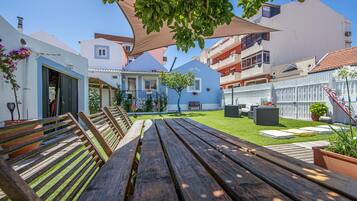 A courtyard with a wooden bench, a small tree, and a white fence.