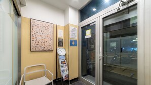 A reception area with a clock, a chair, a bulletin board, and a glass door leading outside.