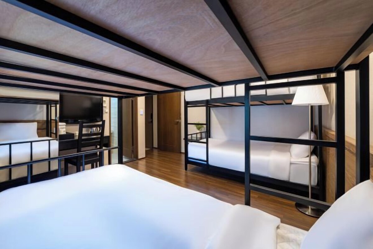 Un intérieur moderne avec des lits superposés, un téléviseur à écran plat et un plafond en bois.