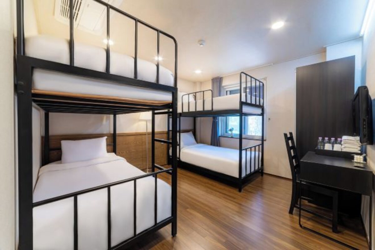 A room with bunk beds, a desk, and a chair.