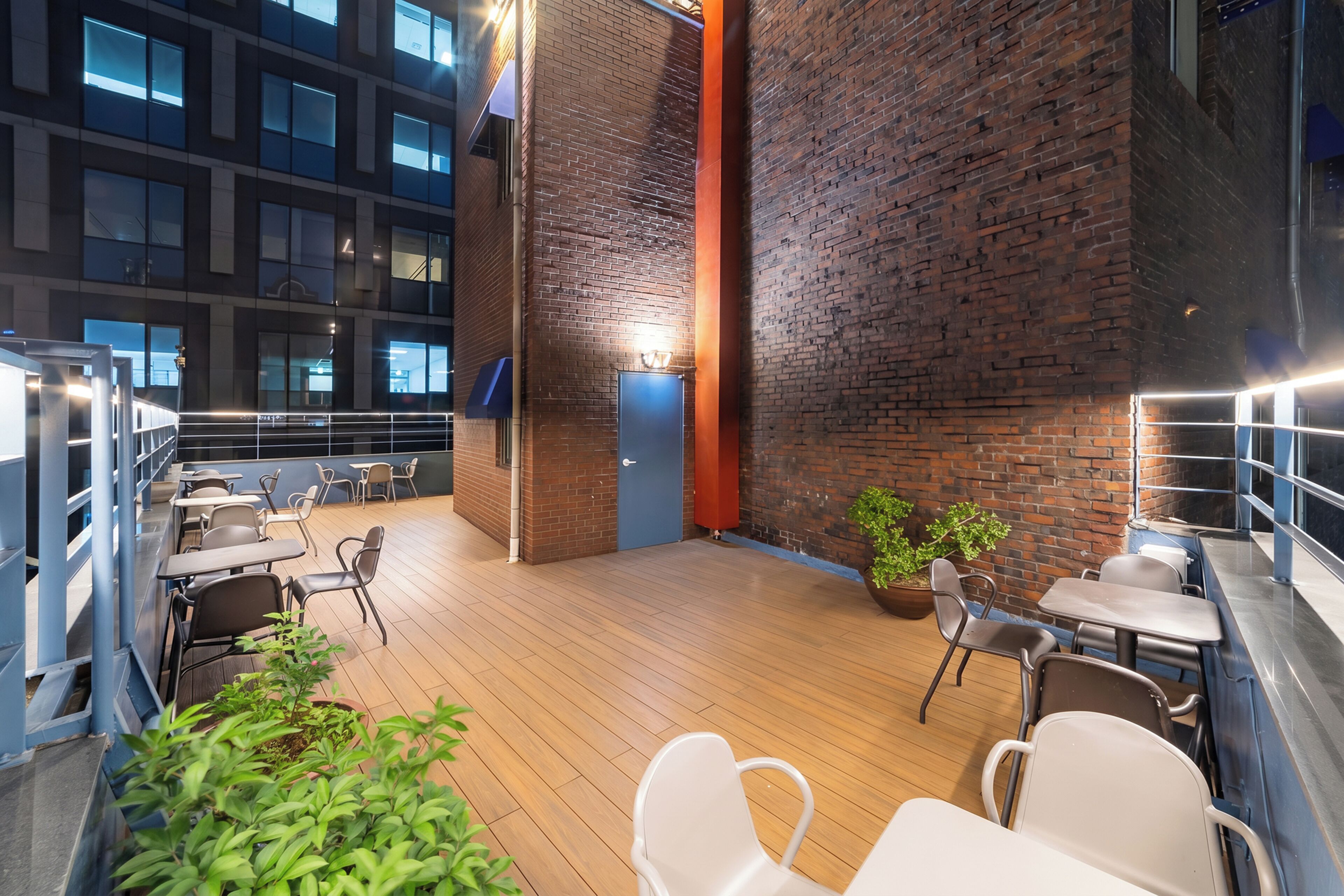 Un espace patio intérieur doté d’un plancher en bois, de différents types de sièges et d’un mur en briques.