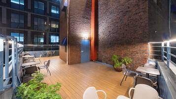 Un espace patio intérieur doté d’un plancher en bois, de différents types de sièges et d’un mur en briques.