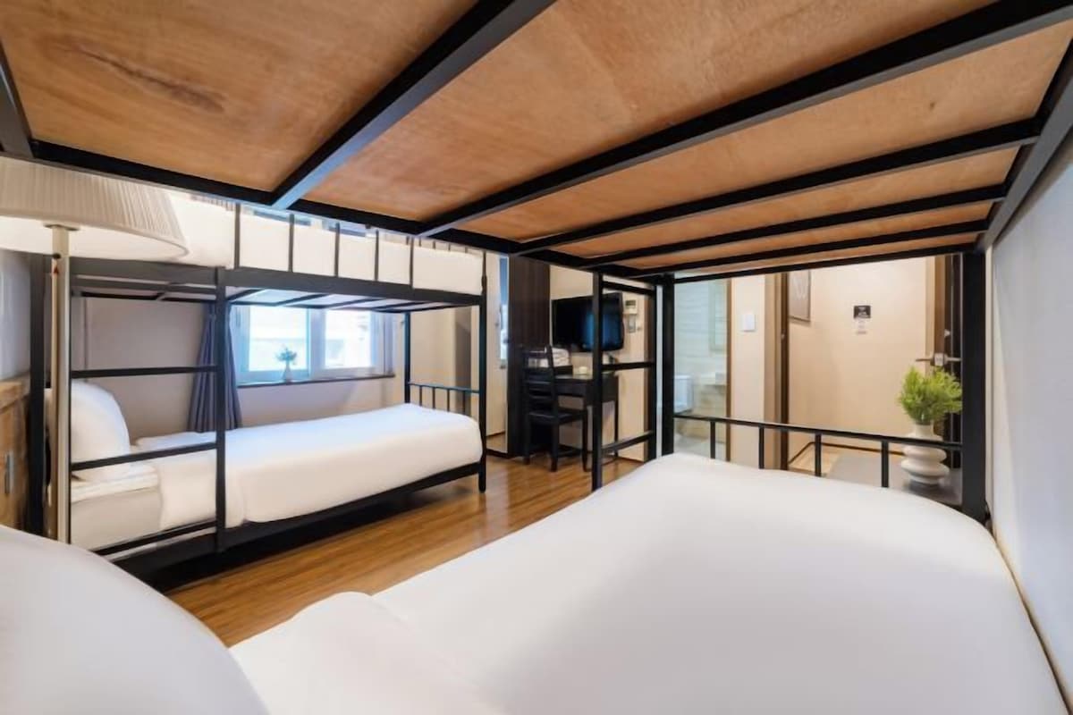 Dormitorio con literas, un escritorio, una lámpara y un televisor.