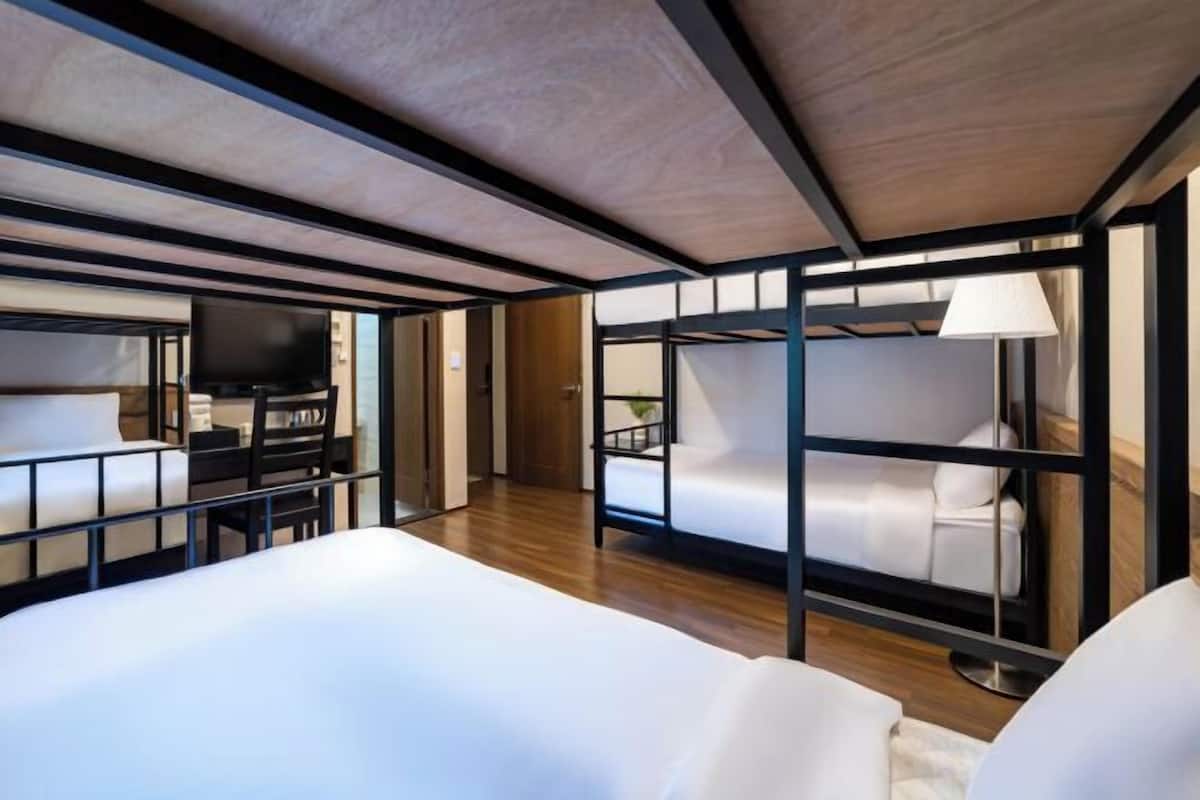 Un intérieur moderne avec des lits superposés, un téléviseur à écran plat et un plafond en bois.