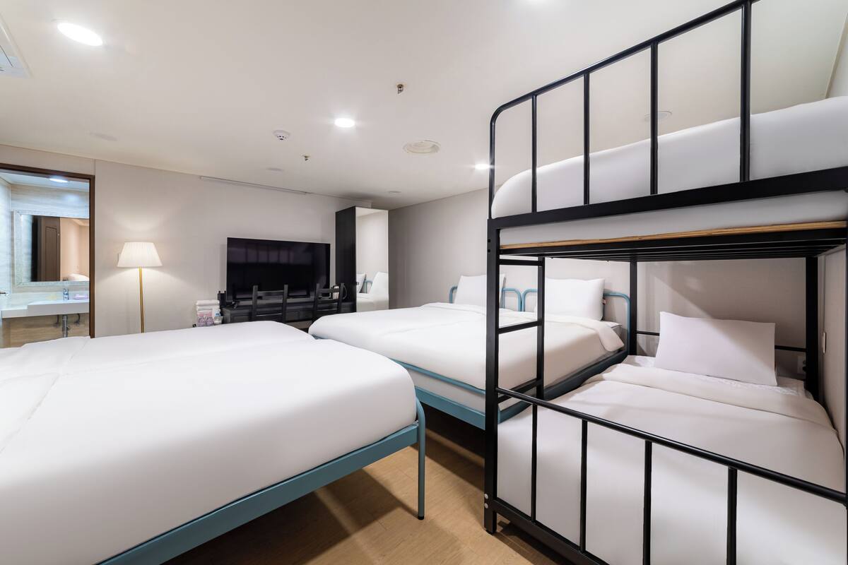 Una habitación de hotel con literas, televisor, escritorio y lámpara.