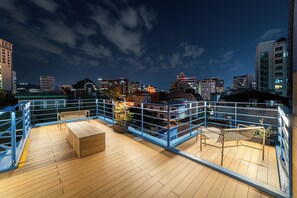 A rooftop terrace with wooden flooring, metal railings, and seating areas. - Soosong Guesthouse gwanghwamun Myeongdong (Seoul)