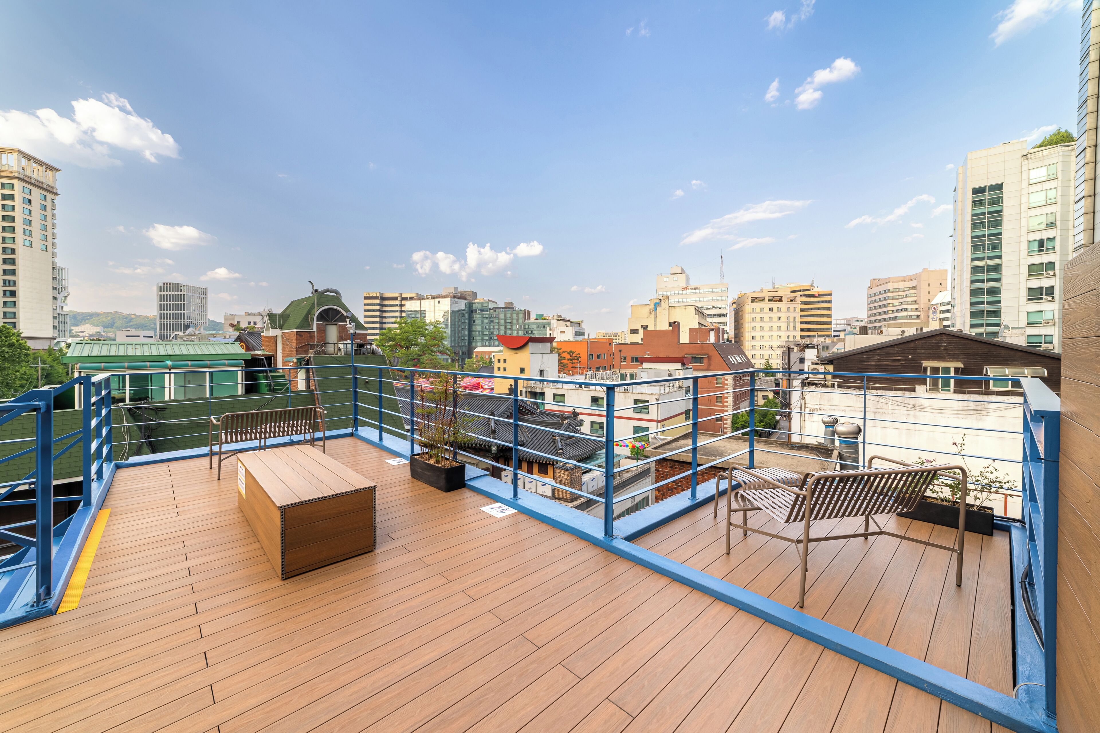 A rooftop deck with wooden flooring, metal railings, and outdoor furniture.