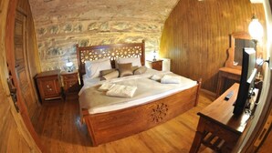 Een slaapkamer met een stenen muur, een houten plafond en een bed met kussens en dekbed.