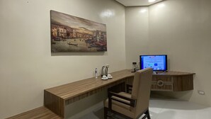 Une chambre moderne avec un bureau en bois, une chaise, un téléviseur et un tableau accroché au mur.