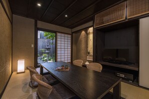A traditional Japanese-style room with tatami flooring, a low table, and a television. - Rinn Premium Machiya Townhouse Kunpu (Kyoto)