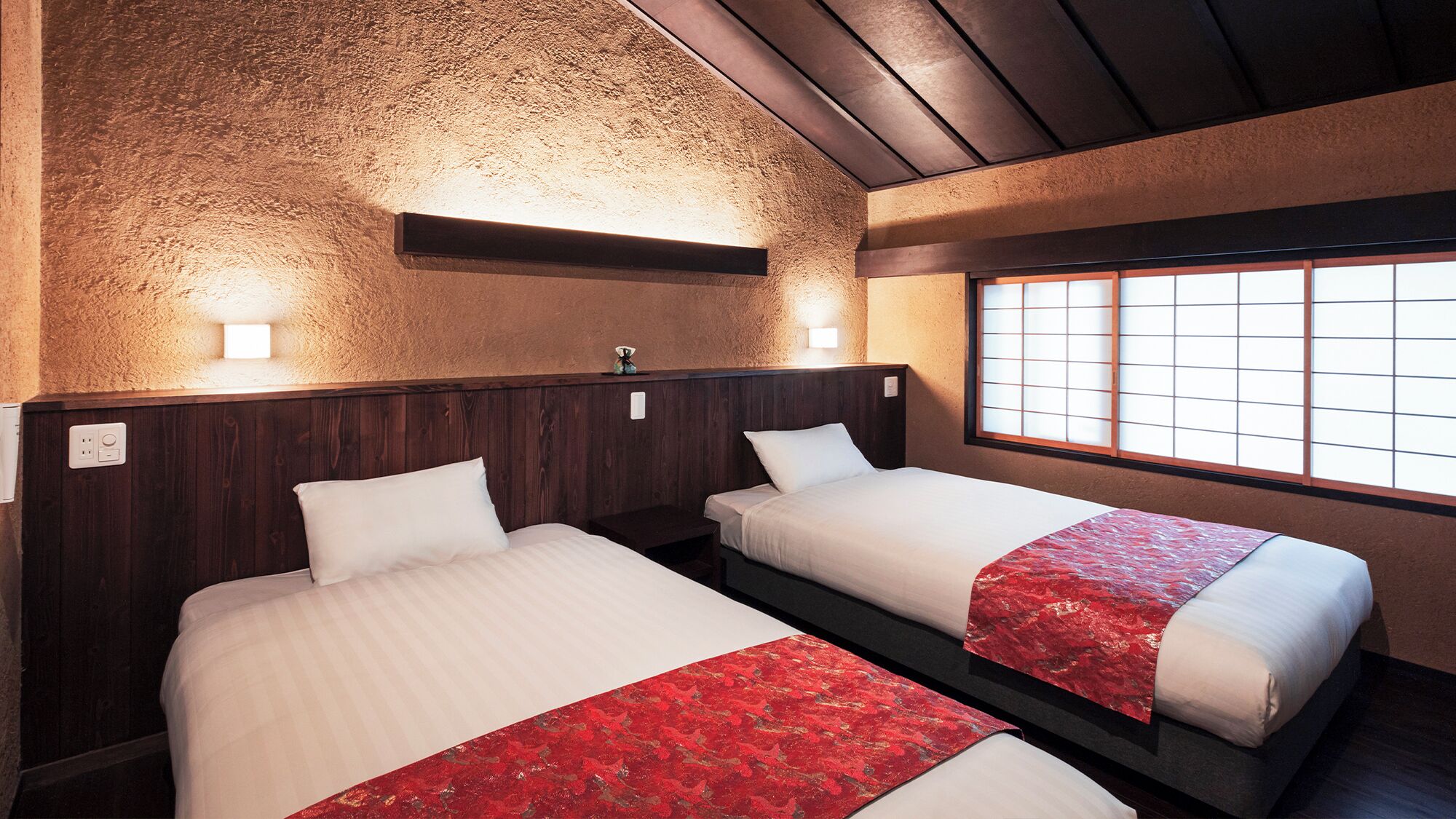 Quarto de hotel com duas camas, parede texturizada, teto de madeira e janela com padrão quadriculado.