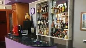 Een bar met een paars aanrecht, drankflessen op de planken, een klok en een koffieapparaat.