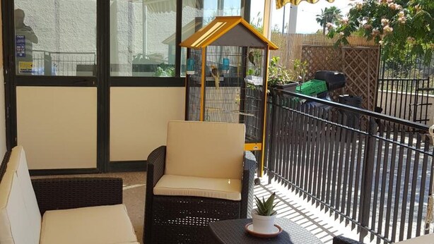 Een terras met rieten meubels en een gestreept zonnescherm.