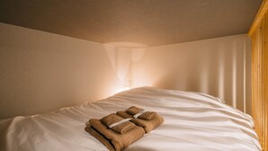 A neatly made bed with white sheets and two brown towels folded on top. - IKIDANE HOUSE OSAKA Kyobashi (Osaka)