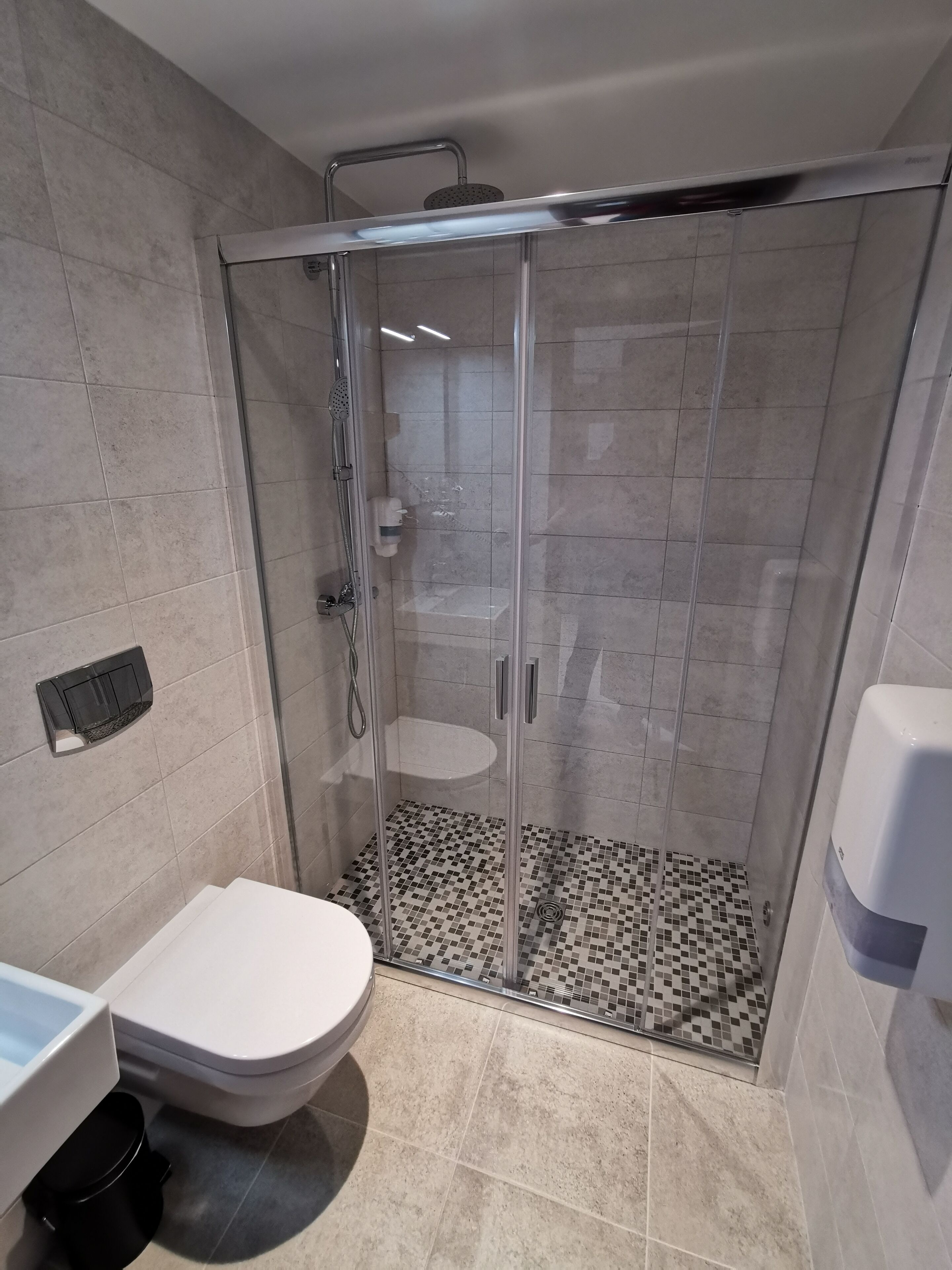 A modern bathroom with a glass-enclosed shower, a toilet, and a sink.