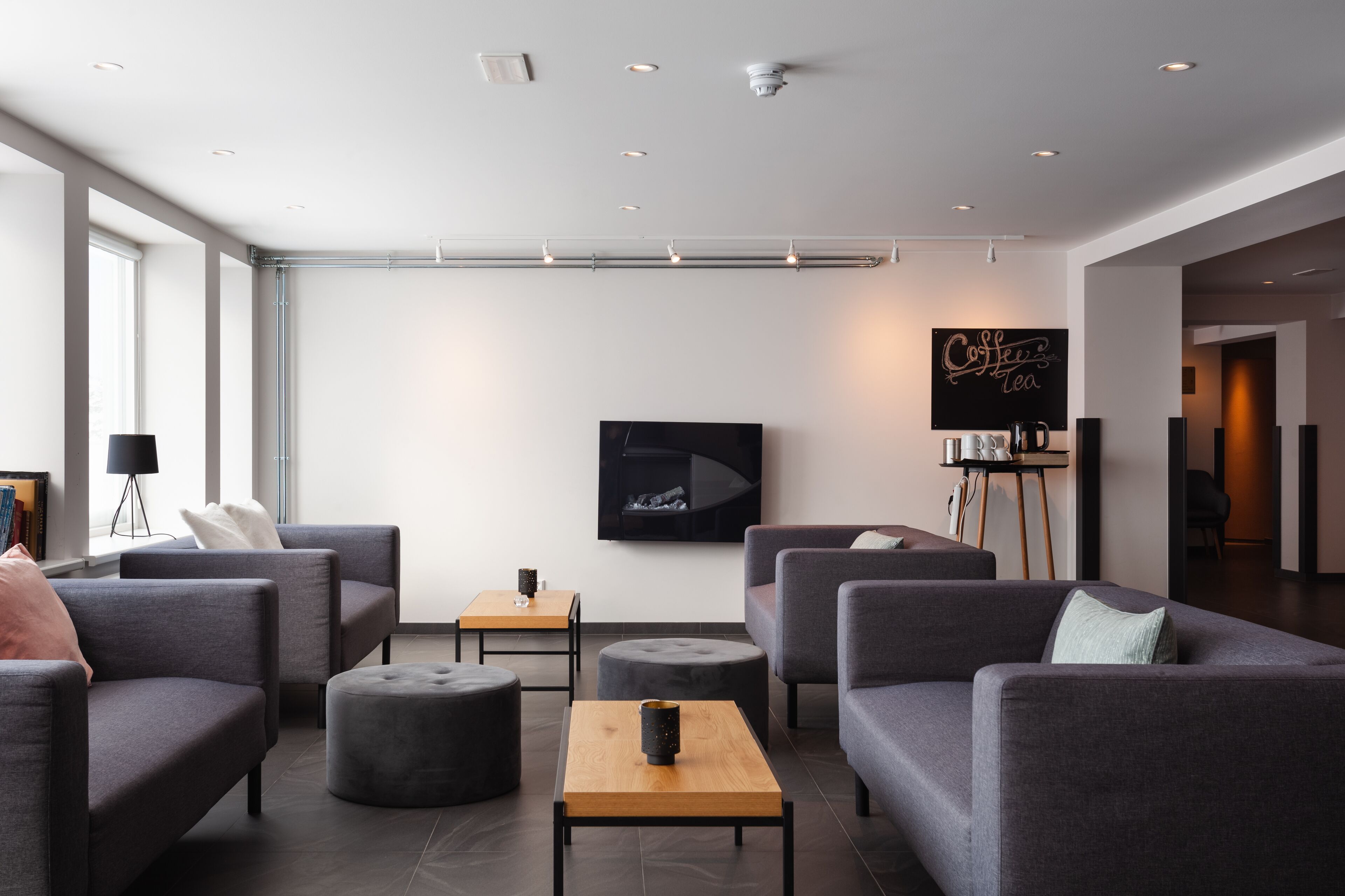 Een moderne woonkamer met grijze banken, een salontafel en een flatscreen televisie aan de muur.