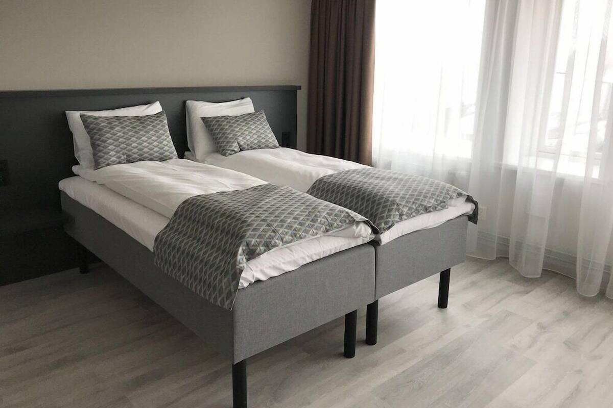 A double bed with a grey headboard and footboard, two pillows, and a grey blanket.