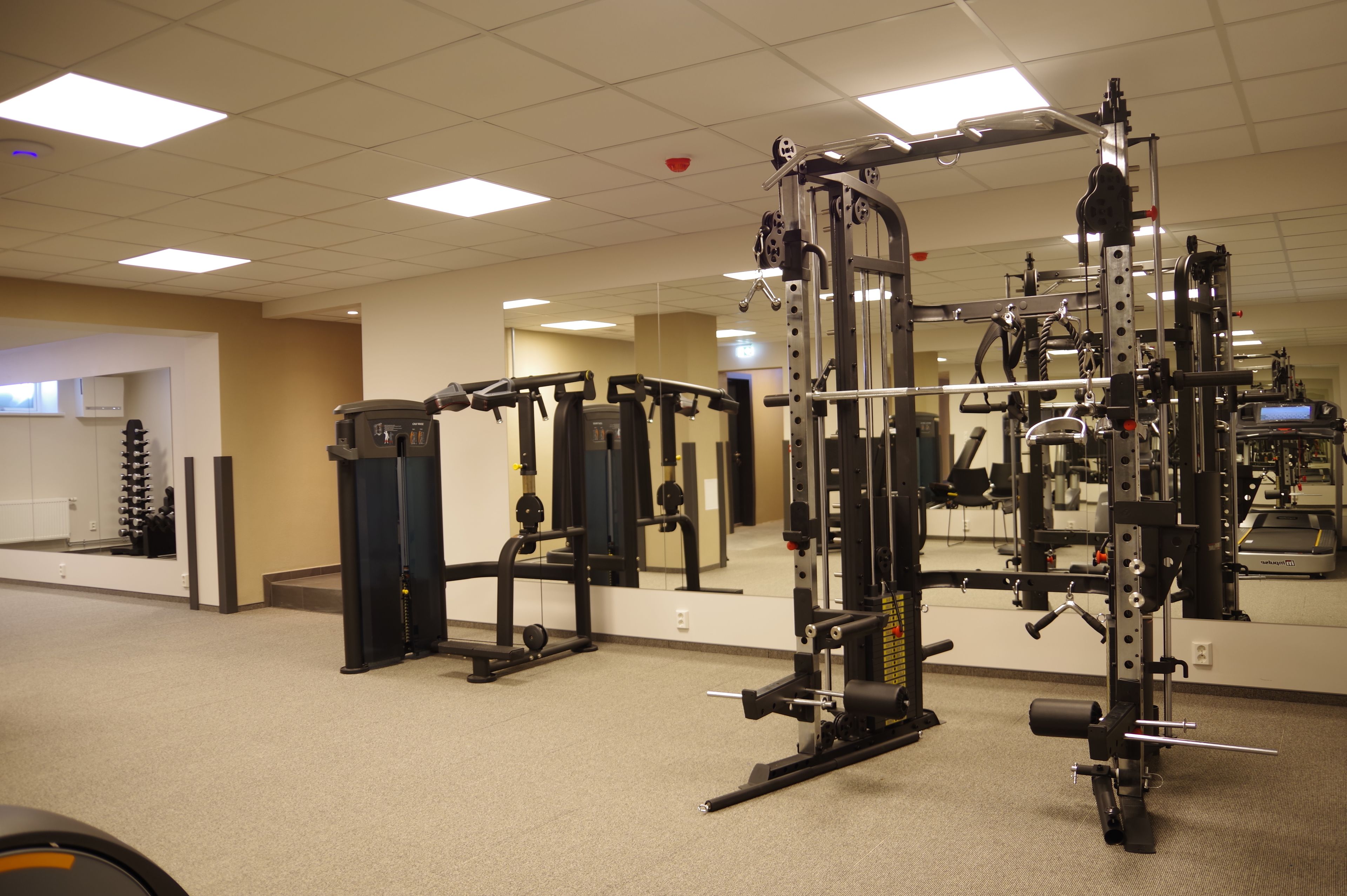 A gym with various exercise machines, a mirror, and a wall-mounted shoe rack.