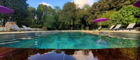 Una piscina al aire libre de temporada, sombrillas