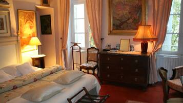 A bedroom with a bed, dresser, chair, and a window with curtains.