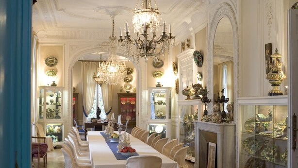 Un comedor formal con una larga mesa, candelabros ornamentados y decoración clásica.