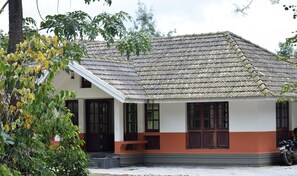 A traditional building with a tiled roof, a porch with benches, and a motorcycle parked outside.