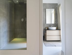 Un baño moderno con ducha, lavamanos y espejo.