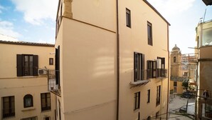 A narrow street with buildings on either side, featuring balconies and a small courtyard. - Suite Dreams (Agrigento)