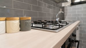 A kitchen with a gas stove, a sink, and three ceramic containers with lids. - Suite Dreams (Agrigento)