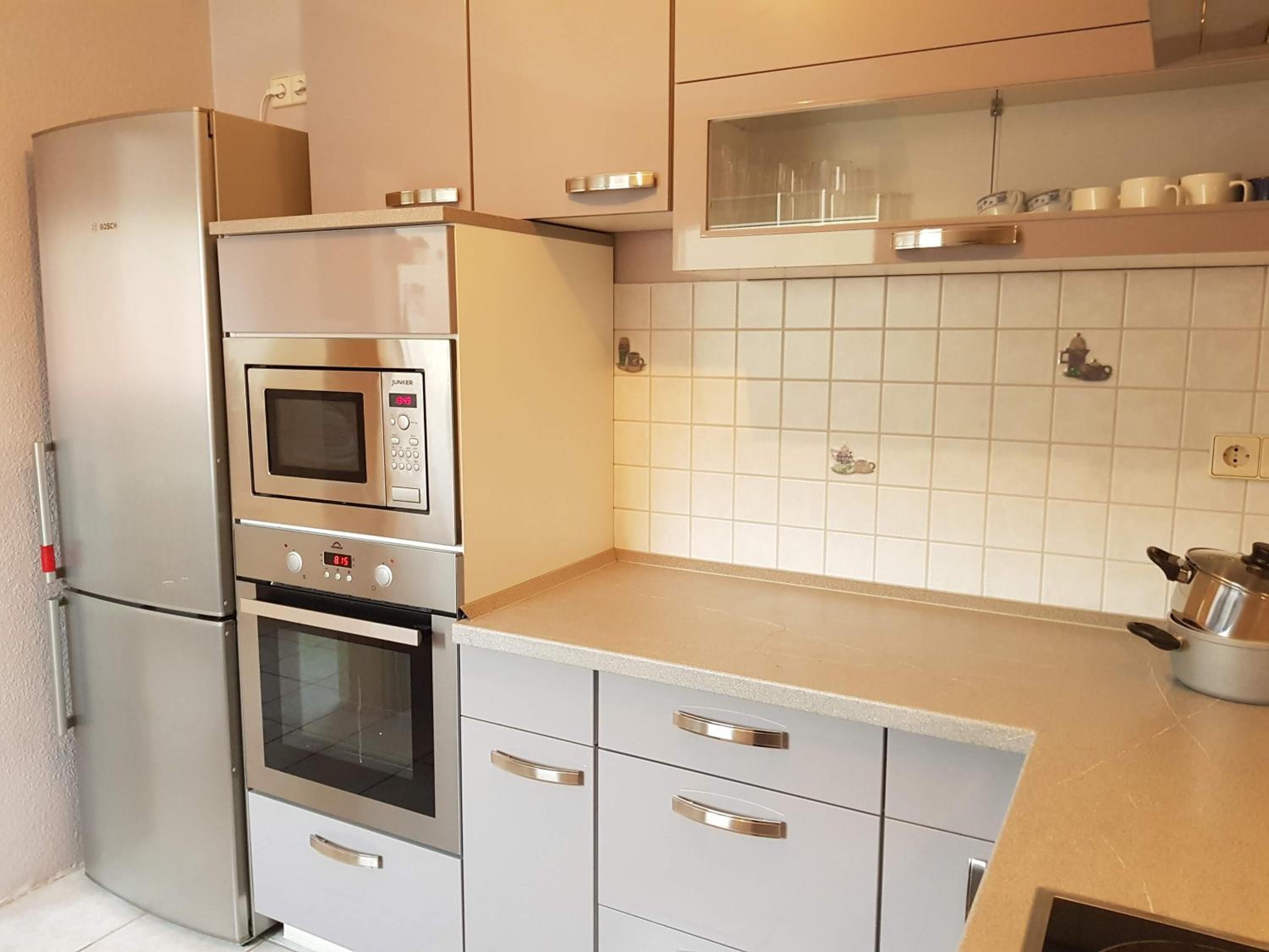 Eine kompakte Küche mit Einbauofen, Mikrowelle und Kühlschrank.