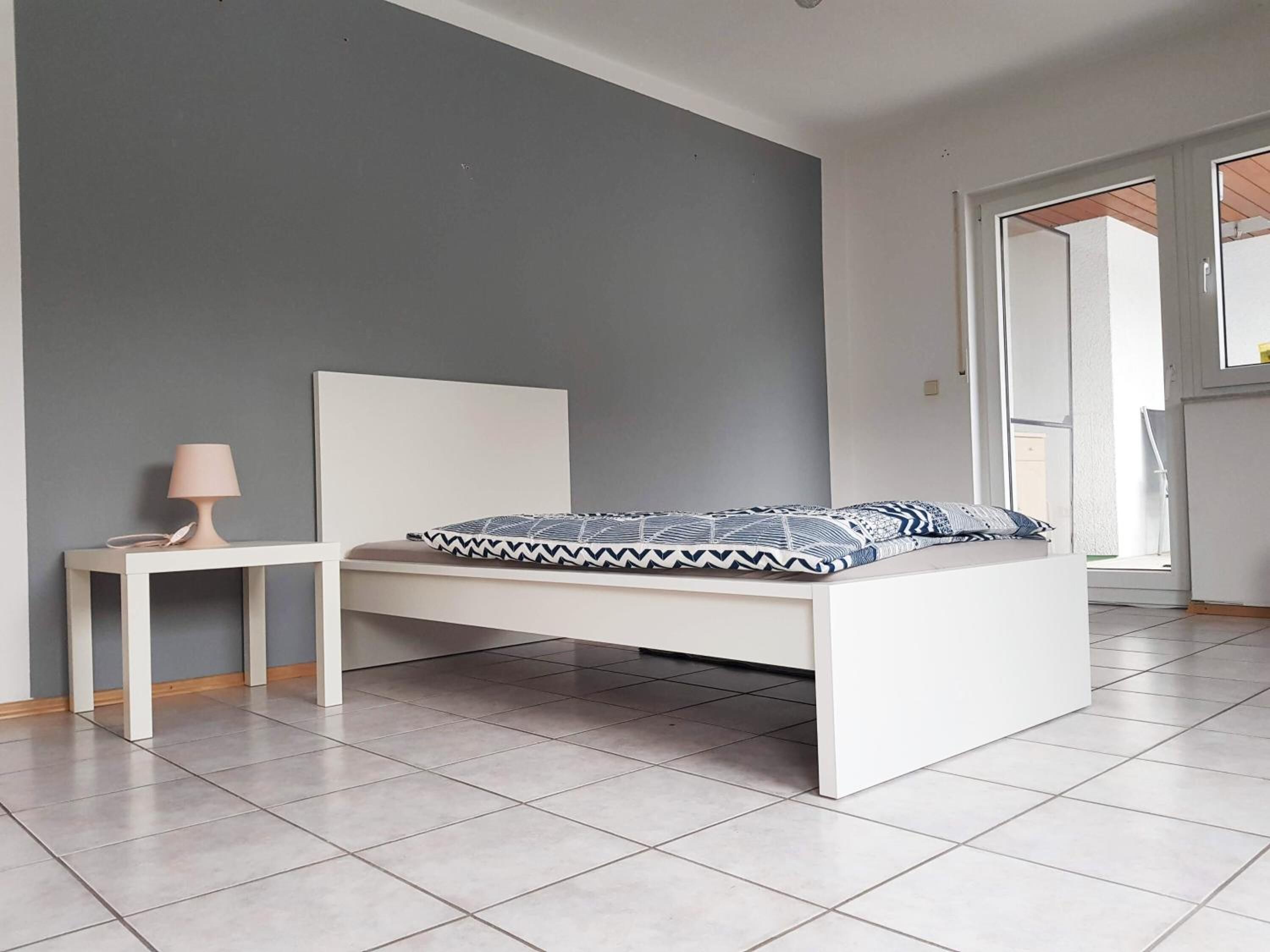 A modern bedroom with a bed, bedside table, and a lamp.
