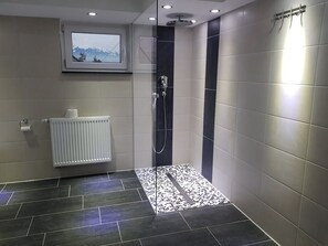 A modern bathroom with a shower, a radiator, and a mounted picture. - My-Skypalace (Obersulm)