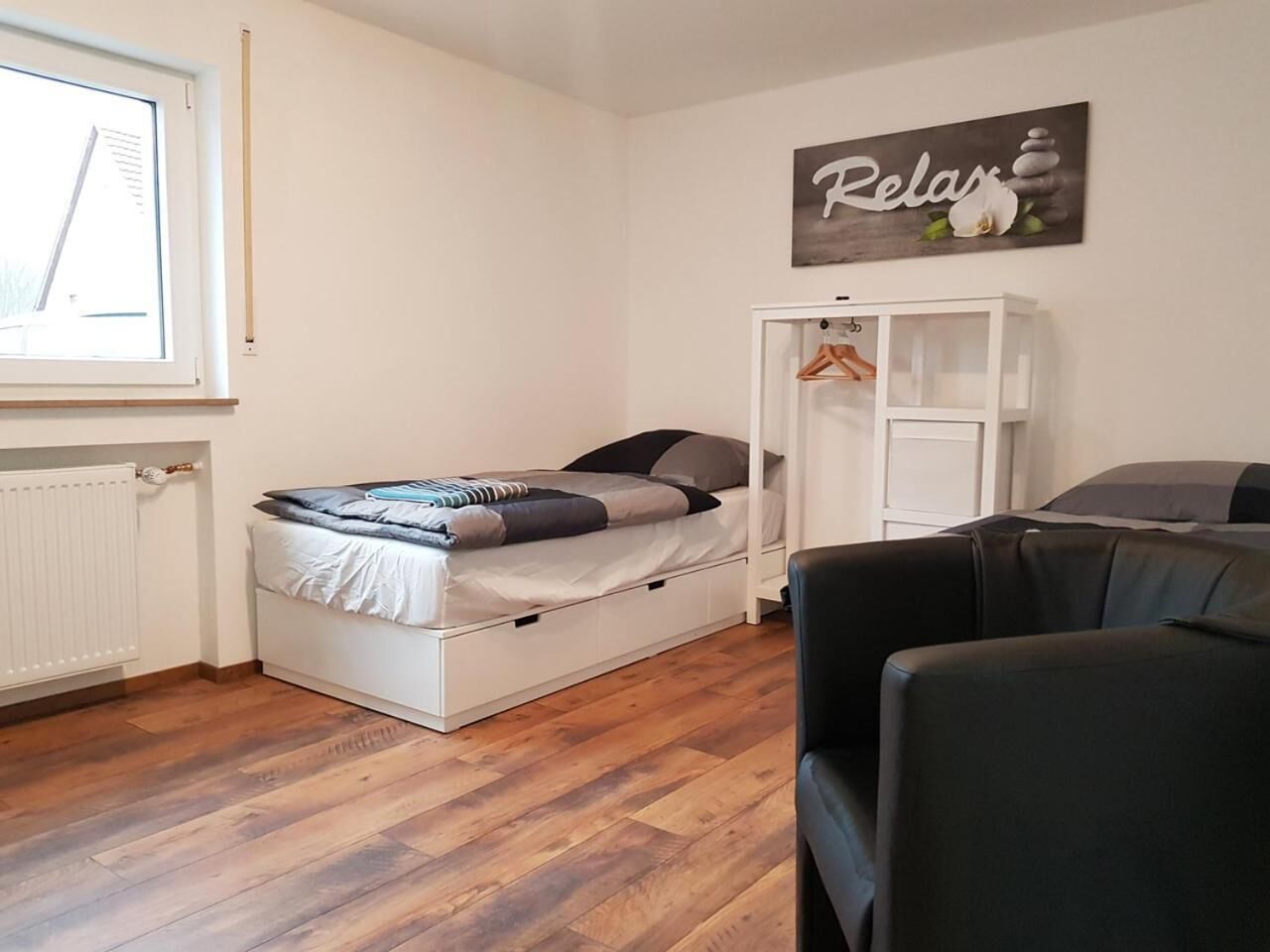 A compact room with a bed, a wardrobe, and a seating area.