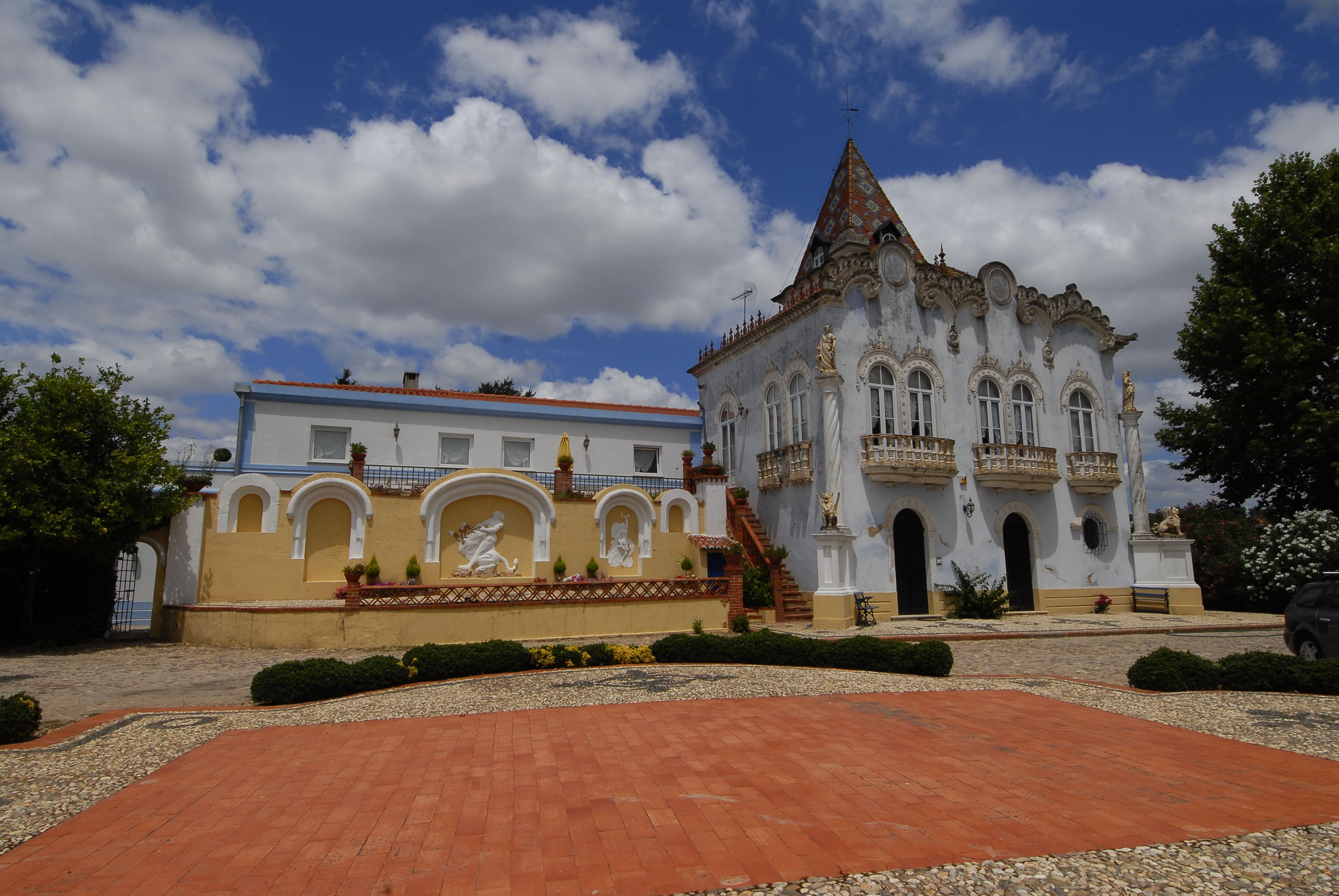 A historic building with a red-tiled courtyard, ornate architecture, and statues.