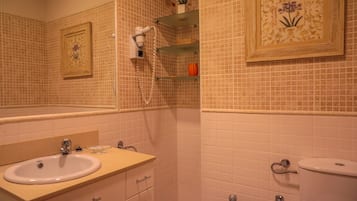 Une salle de bain équipée d’un lavabo, d’un miroir, de toilettes et d’étagères contenant des articles de toilette.