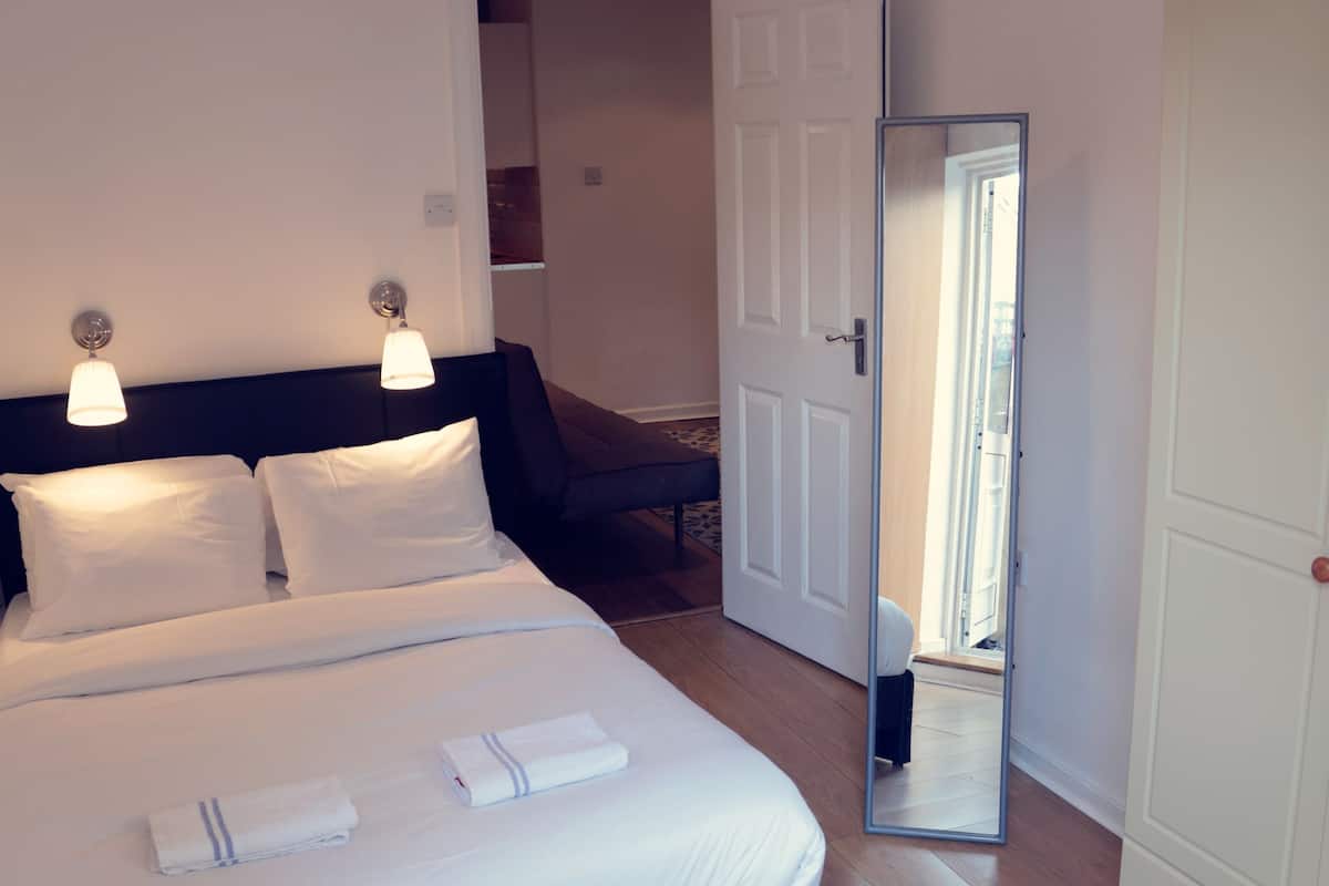 A bedroom with a bed, bedside lamps, a wardrobe, and a mirror.