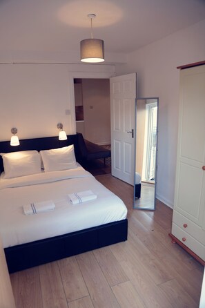 A bedroom with a bed, bedside lamps, a wardrobe, and a mirror.