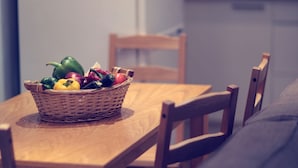 Ein Esstisch mit einem Korbkühler voller verschiedener Früchte und Gemüsesorten.