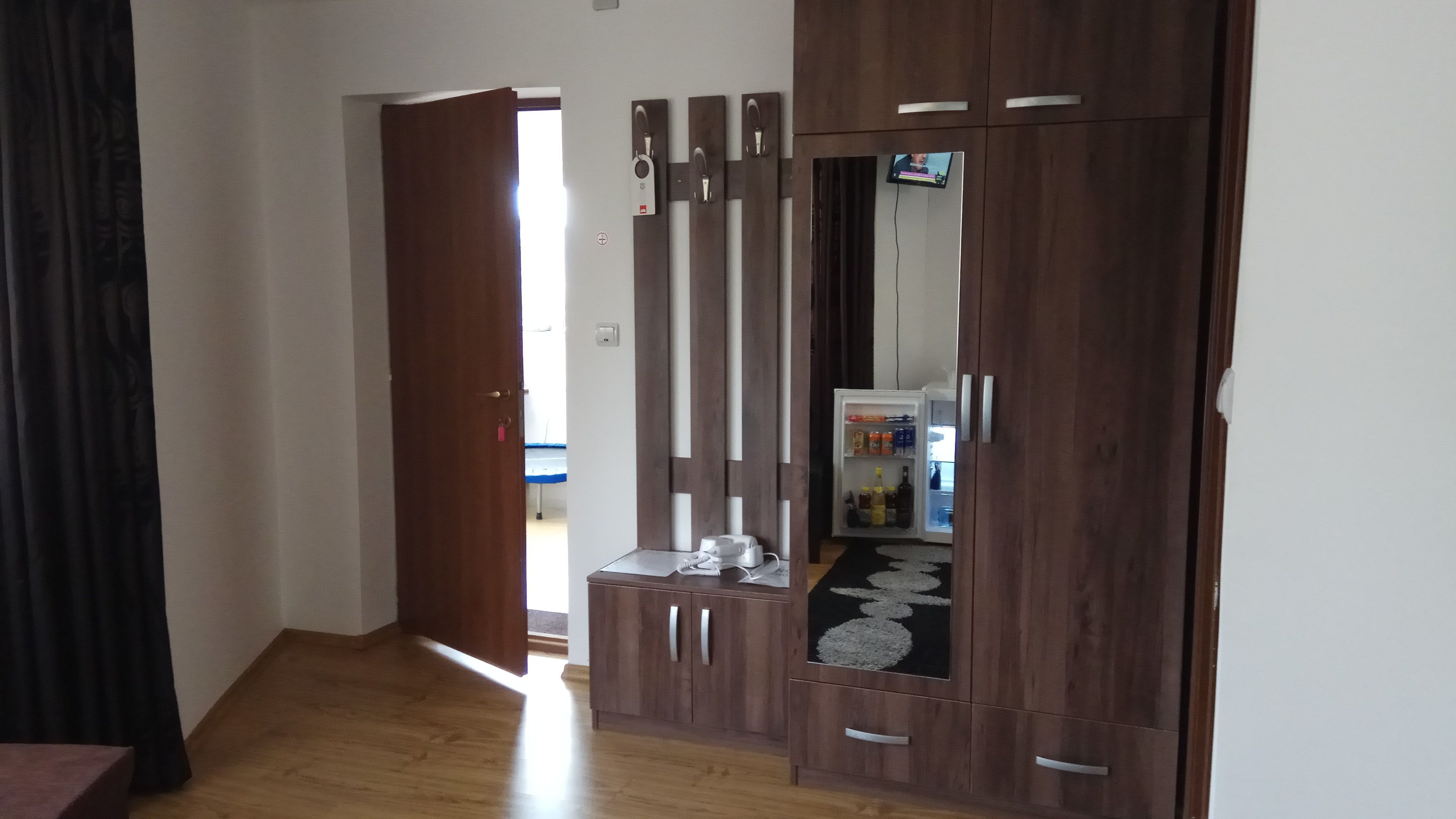 Une pièce avec une armoire en bois, une petite table avec un téléphone et un miroir.