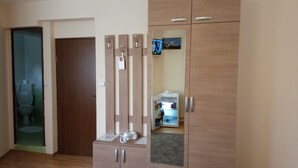 Una habitación con un armario de madera, un pequeño mueble con teléfono y un espejo que refleja un baño con inodoro y lavabo.