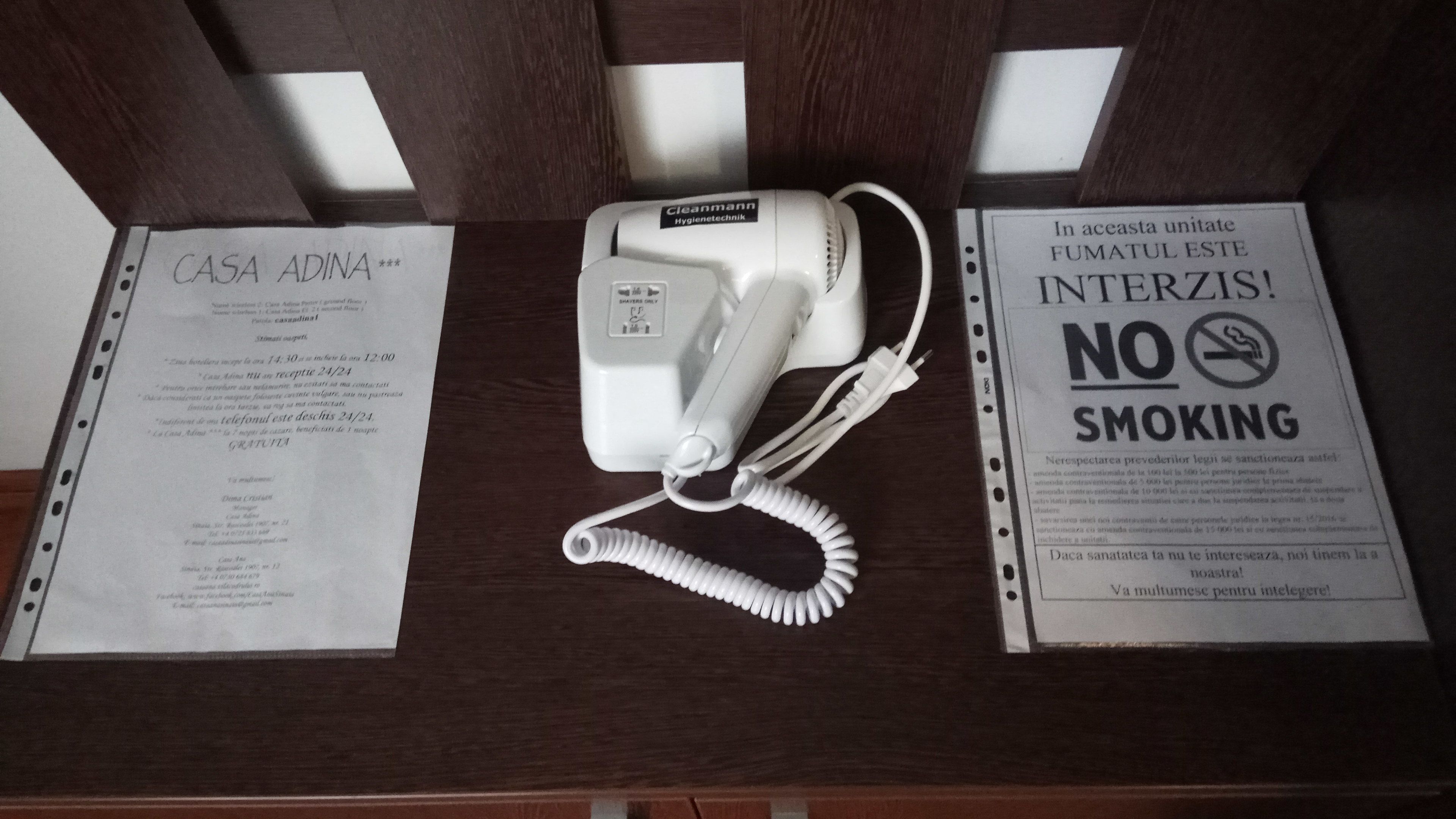 A telephone, a sign with a smoking prohibition, and a document titled 'CASA ADINA'.
