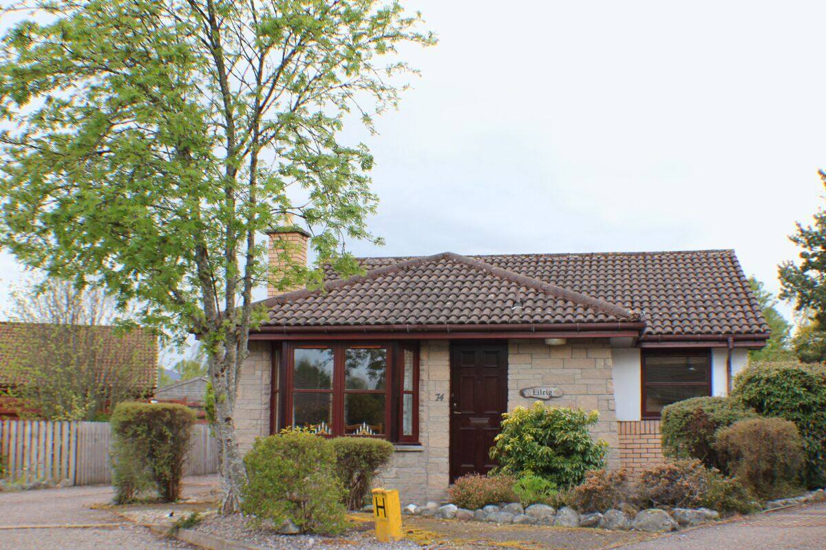 A two-story house with a tiled roof, a stone facade, and a front door with a window above it.