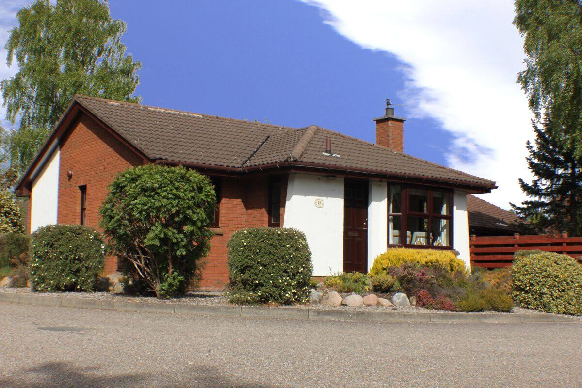 A two-story house with a brick exterior, a tiled roof, and a small front porch.