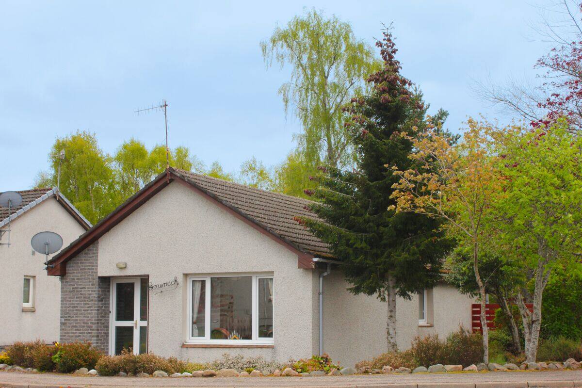 A small, single-story building with a sloped roof, a visible chimney, and a satellite dish.