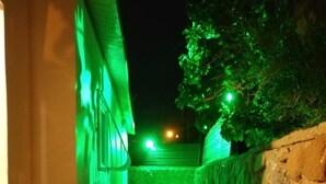 A narrow stone-walled pathway leading to a building with a green-lit exterior. - Eden's sweet place (Eilat)